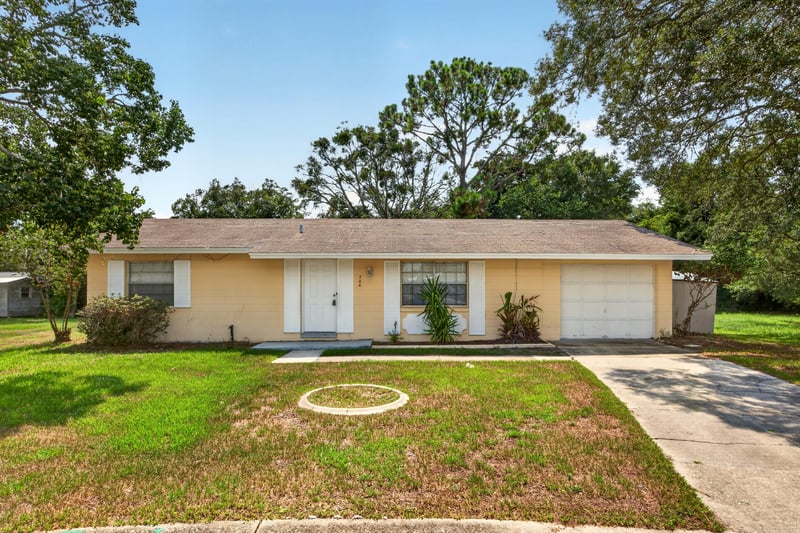 Front exterior with tan siding, two-car garage, and lawn at 328 Palos Ct, St. Augustine, FL