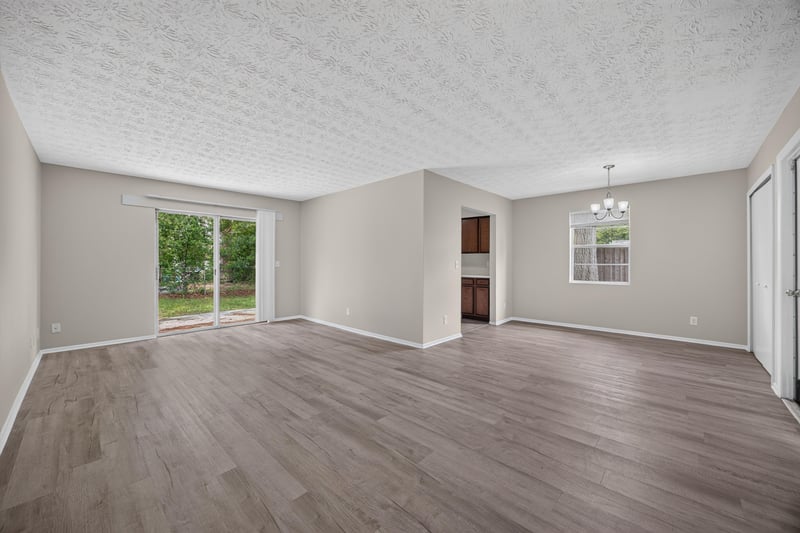 Empty living room with wood-look flooring and sliding glass door at 1083 Stokes St, Jacksonville, FL