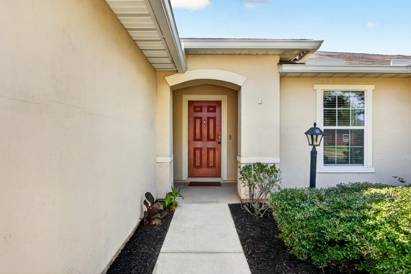 Front entry with arched doorway and red door at 7545 Lirope St, Jacksonville, FL 32244