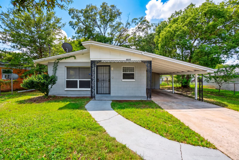 Front exterior with covered carport and green lawn at 4030 Leonard Cir W, Jacksonville, FL 32209