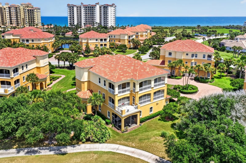 Aerial of community rooftops with ocean and high-rises in Palm Coast, FL