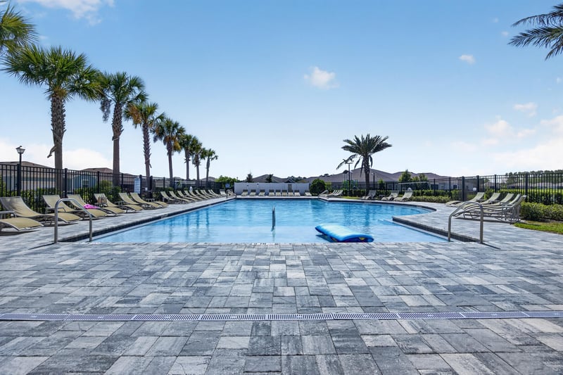 Community pool deck lined with palm trees in Highland Chase