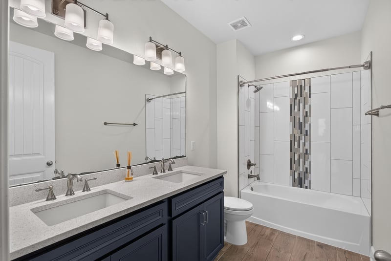 Bathroom with navy vanity and tub-shower combo at 855 Flach Dr, St. Johns, FL