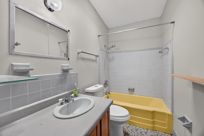 Bathroom with tiled tub surround and yellow accent at 11462 Elane Dr, Jacksonville, FL