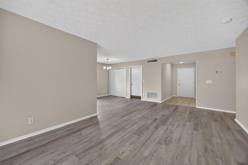 Empty room opening to kitchen with wood-look flooring at 1083 Stokes St, Jacksonville, FL