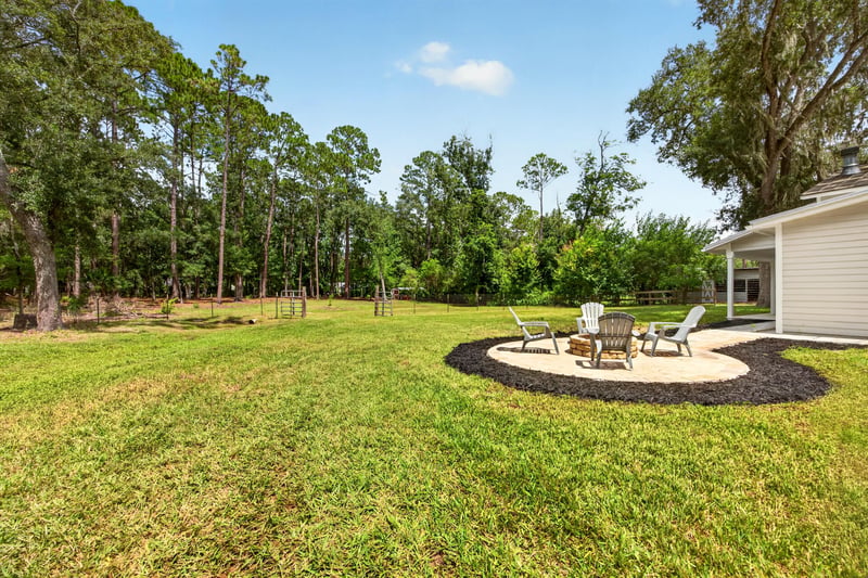 Open lawn with distant fire pit area at 1161 Whispering Pines Rd, Jacksonville, FL 32259