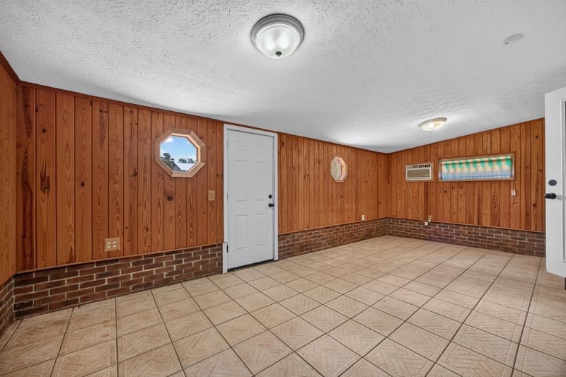 Wood-paneled bonus room with tile flooring and round window at 6757 Deer Springs Rd, Keystone Heights, FL 32656