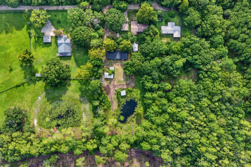 Aerial overview of the home, pond, and wooded acreage at 55520 Jewel-Thomas Rd, Callahan, FL 32011