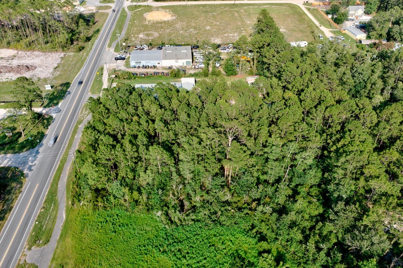 Aerial of the tree-covered lot with storage buildings in the distance at 4393 Co Rd 218, Middleburg, FL 32068