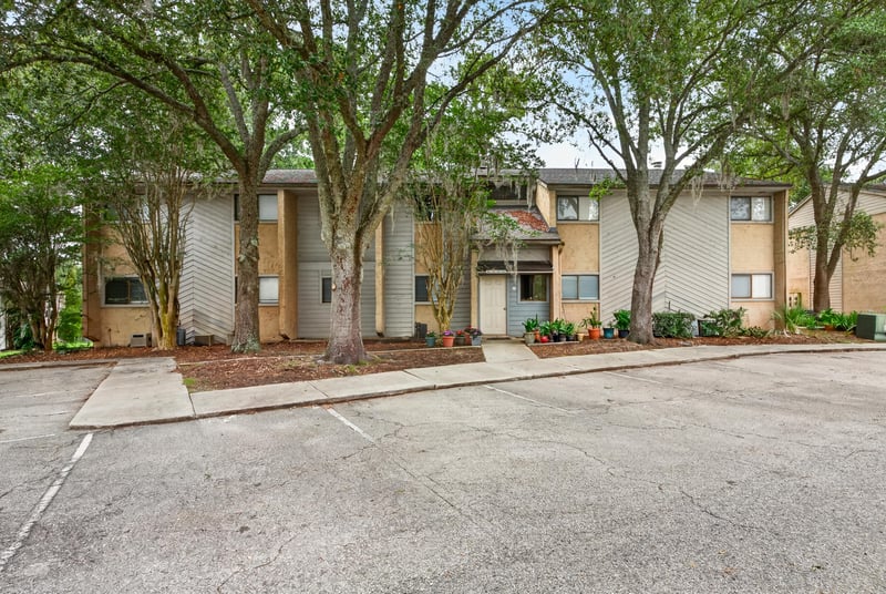 Front exterior of the condo building with mature trees at 3801 Crown Point Rd unit 2061, Jacksonville, FL 32257