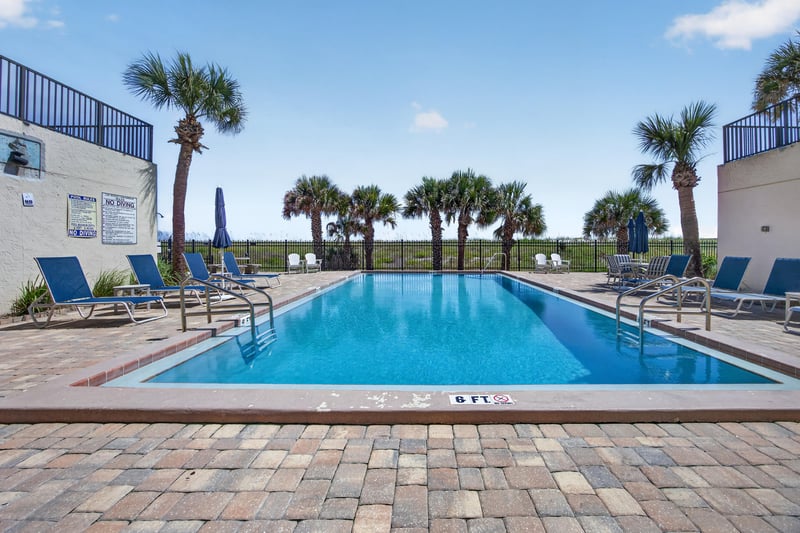 Community pool with palm trees and lounge chairs at 601 1st St S, Jacksonville Beach