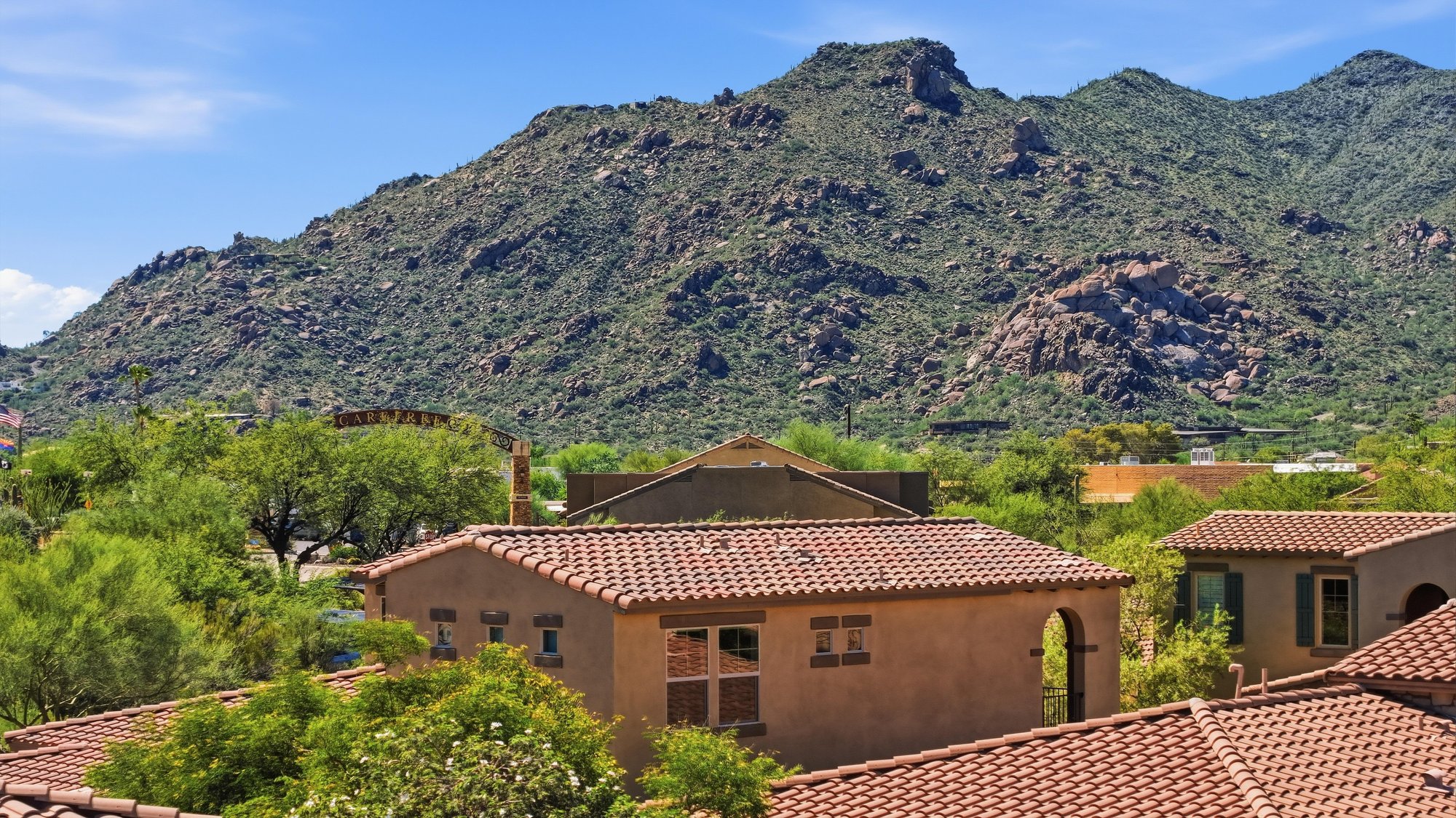 Aerial of a Tuscan-style home below a green mountain
