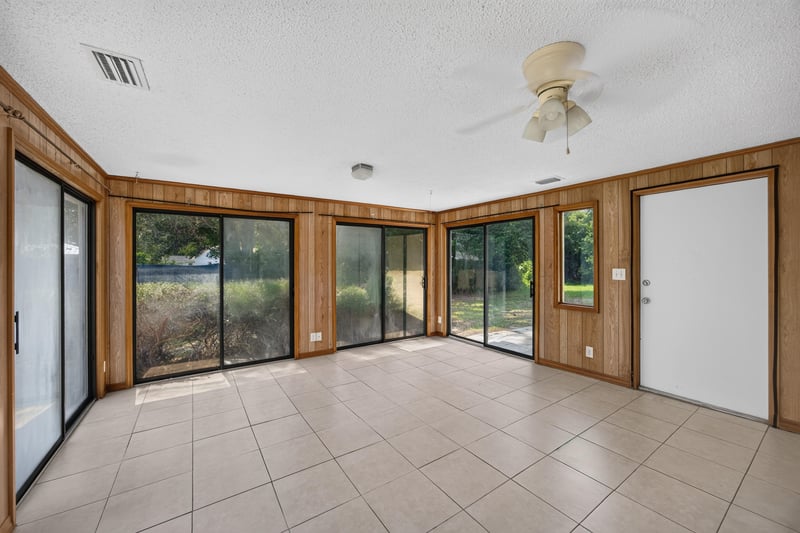 Tiled sunroom with wood-paneled walls and sliding glass doors at 328 Palos Ct, St. Augustine, FL