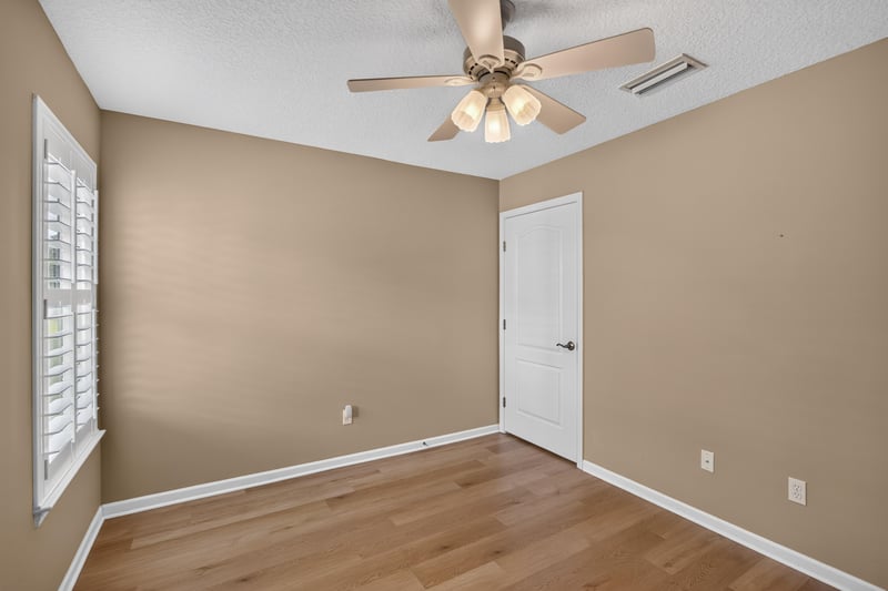 Bedroom with tan walls and wood floors at 2131 E Stone Creek Dr, Fleming Island, FL