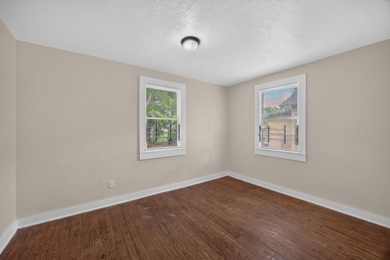 Empty bedroom with two windows and wood floors at 1473 State St W, Jacksonville, FL 32209