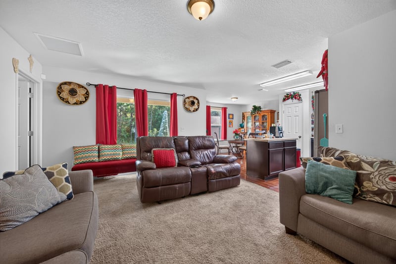 Living room with leather sofas and carpet flooring at 518 Matecumbe Ct, Macclenny, FL
