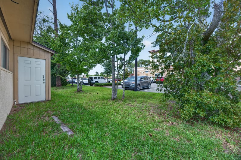 Side exterior with door, lawn and trees at 1543 Kingsley Ave #19, Orange Park, FL 32073