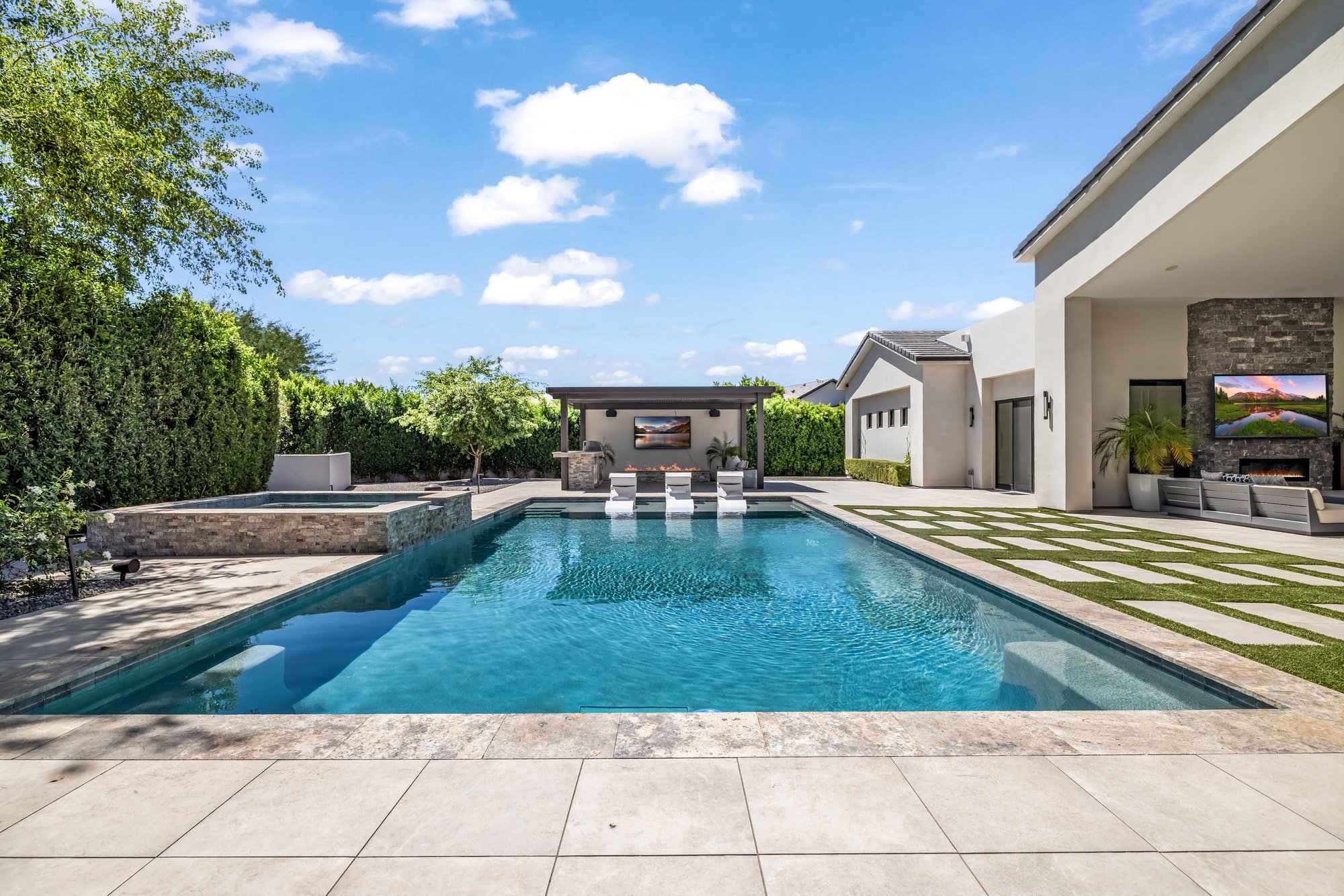 Long pool with a stone spa, in-pool loungers and a ramada at the far end