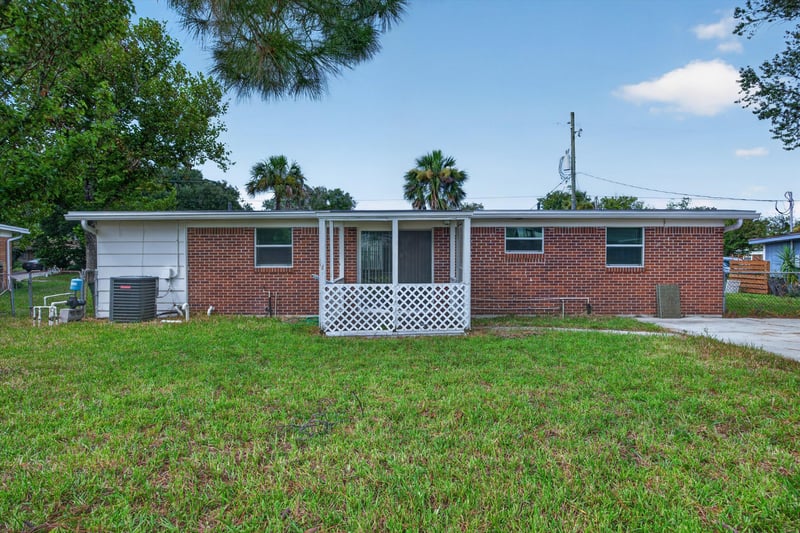 Backyard with brick home and white screened porch at 87 Saratoga Cir S, Atlantic Beach, FL