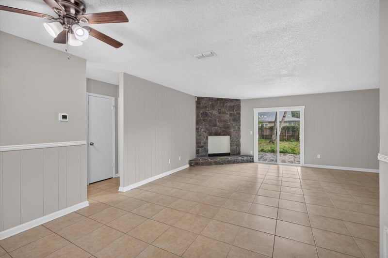 Living room with ceiling fan and stone accent wall at 1040 Willow Cove Ct E, Jacksonville, FL 32233