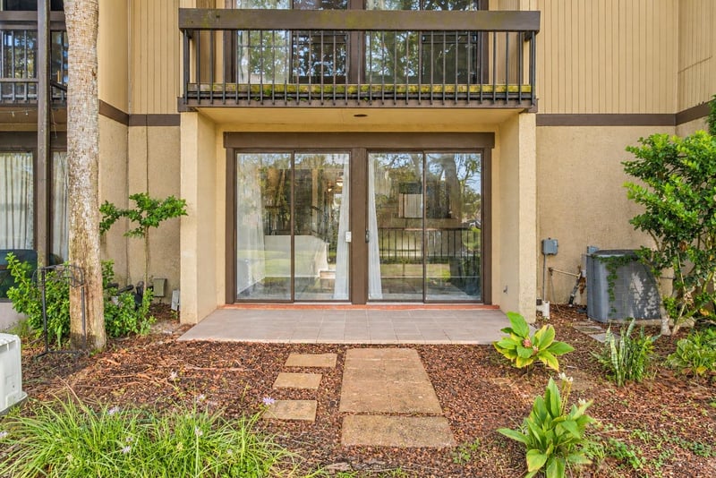Rear patio and sliding doors with balcony above at 7703 Las Palmas Way
