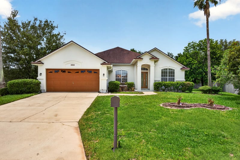 Front exterior with tile roof, paver driveway, and two-car garage at 2480 Ridge Will Dr, Jacksonville, FL 32246