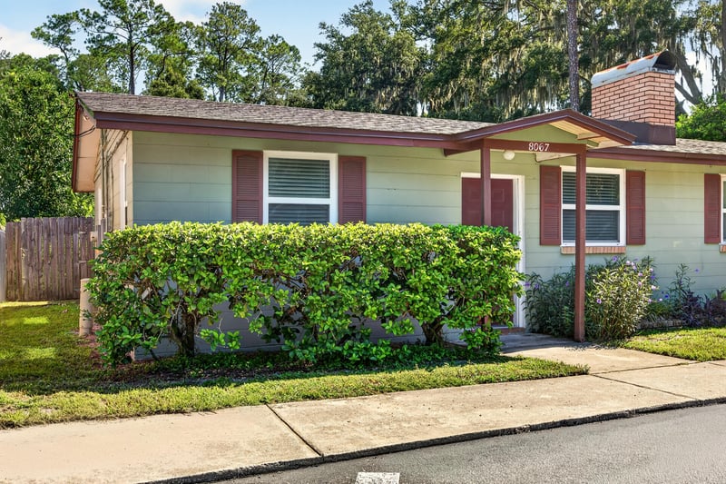 Front exterior with landscaped hedges and red door at 8067 Parental Cir, Jacksonville, FL 32216