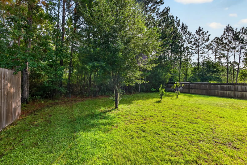 Wooded side yard bordering the fenced lawn at 518 Matecumbe Ct, Macclenny, FL