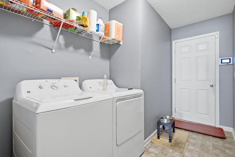 Laundry room with washer-dryer and wire shelving at 7392 Timber Falls Ct