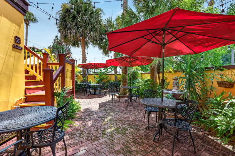 Courtyard patio with red umbrellas and seating at 115 Cordova St, St. Augustine, FL