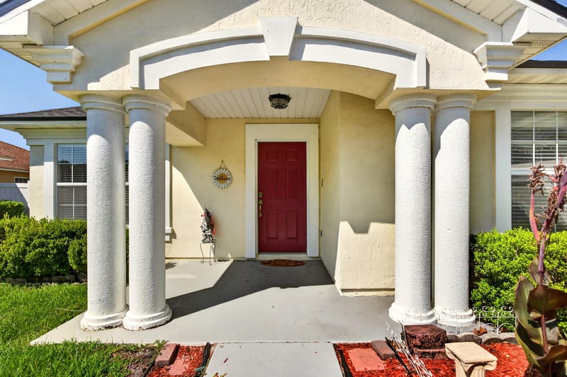 Covered entry with columns and red front door at 2282 Justin Lake Dr, Jacksonville, FL
