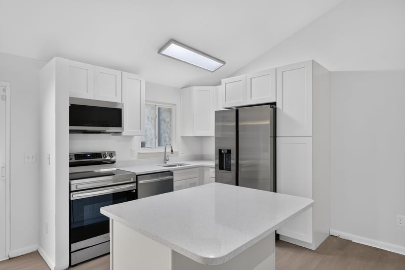 Kitchen with white cabinets and island, virtually staged at 8177 Virgo St, Jacksonville, FL 32216