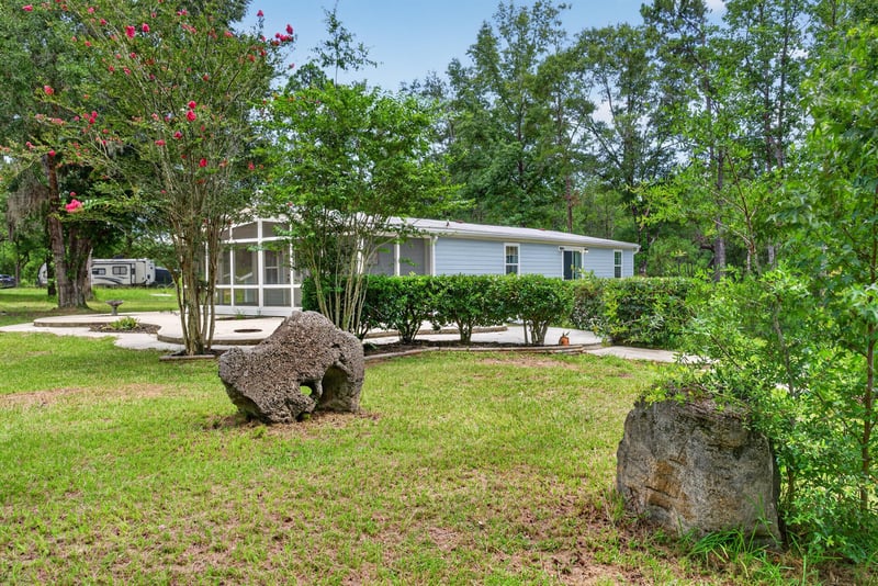 Aerial backyard view with large rocks and trees at 4890 McAllister Rd, Middleburg, FL 32068