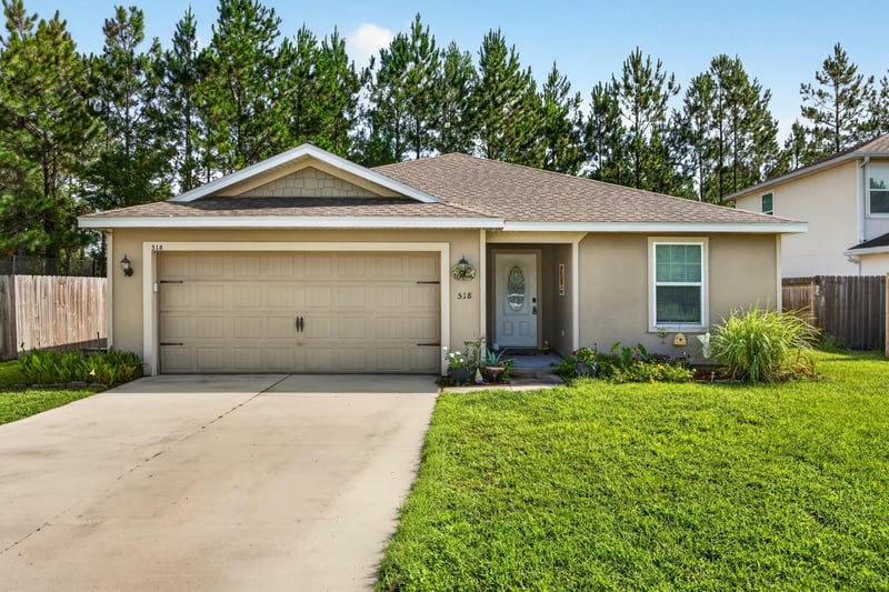 Front exterior view of tan stucco home with lawn at 518 Matecumbe Ct, Macclenny, FL