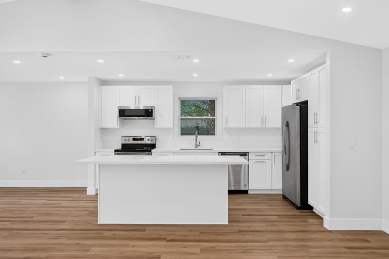 Kitchen with white cabinets, island, and stainless appliances at 8453 Boysenberry Ln W, Jacksonville, FL