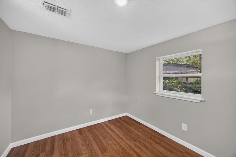 Empty living room with wood floor and window at 7015 Miss Muffet Ln N, Jacksonville, FL 32210