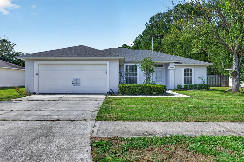 Front exterior view of garage and landscaped yard at 9691 Nelson Forks Dr, Jacksonville, FL 32222