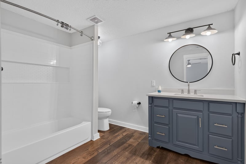 Bathroom with round mirror and dark wood vanity at 4890 McAllister Rd, Middleburg, FL 32068