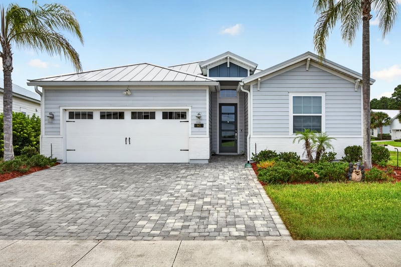 Street view of the light blue siding, glass front door and paver driveway at 91 Tilloo Ct, St. Johns, FL