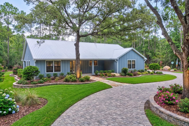 Front exterior with metal roof and curved paver driveway at 4800 Acacia St, Middleburg, FL 32068