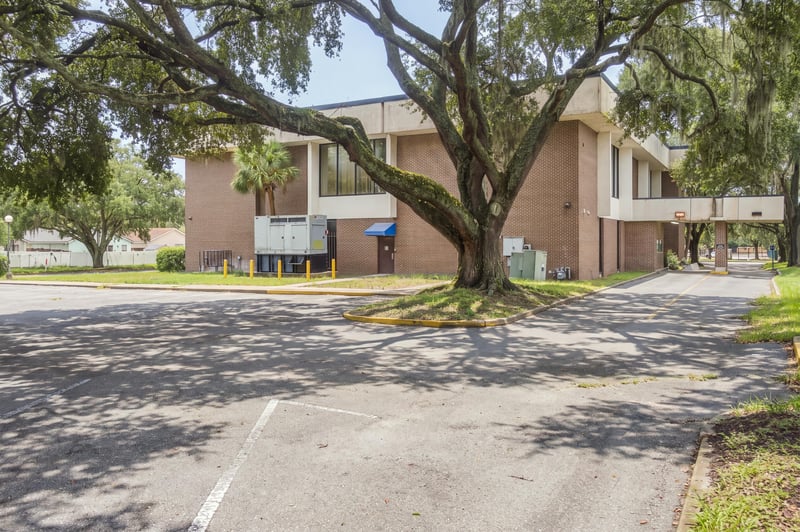 Parking lot and brick building exterior with oak trees at 101 Scholars Wy