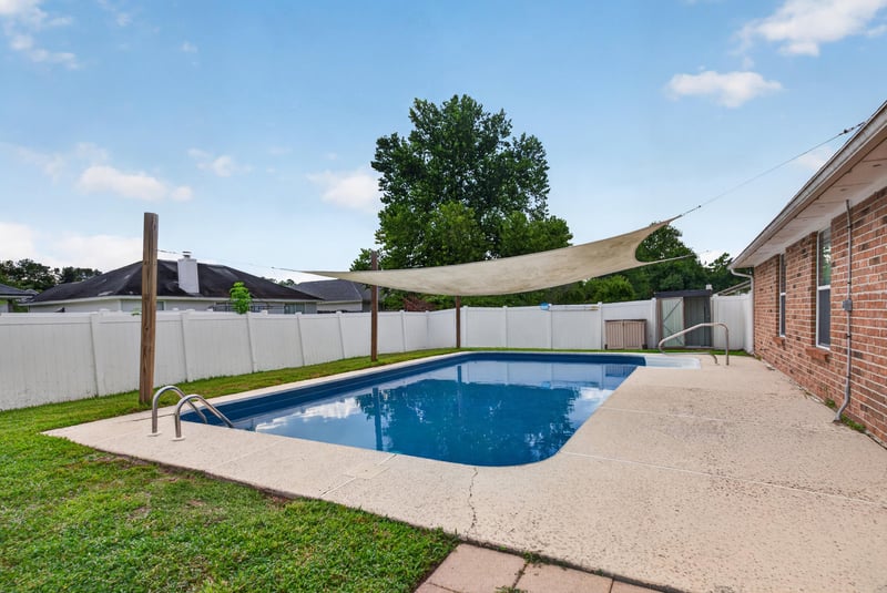 Backyard pool with shade sail and privacy fence at 2164 Orangewood St, Middleburg, FL 32068