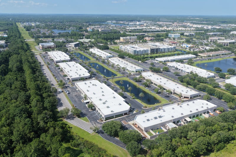 Aerial view of building rooflines and parking with pond at 10550 Deerwood Park Blvd, Jacksonville, FL 32256