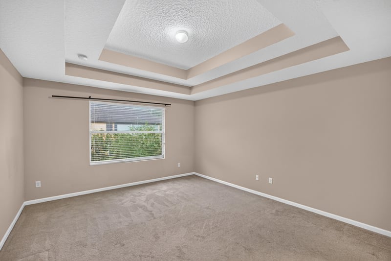 Carpeted bedroom with tray ceiling and window at 3762 Hartsfield Forest Cir, Jacksonville, FL 32277