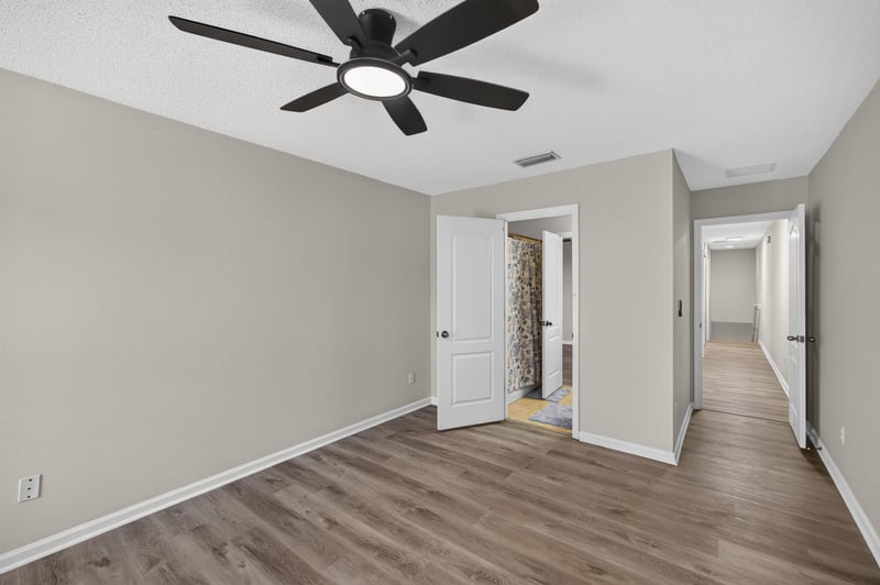 Bedroom with multiple doors and wood-look flooring at 7723 Playschool Ln, Jacksonville, FL