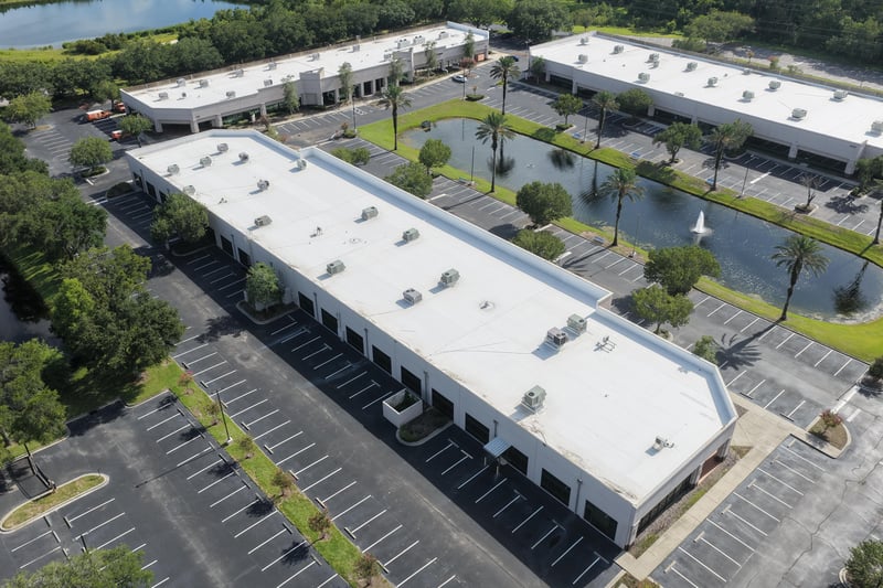 Aerial view of a building roof with parking lot and pond at 10550 Deerwood Park Blvd, Jacksonville, FL 32256
