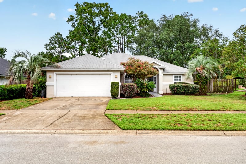 Front exterior with two-car garage and landscaped lawn at 12949 Chets Creek Dr S, Jacksonville, FL 32224