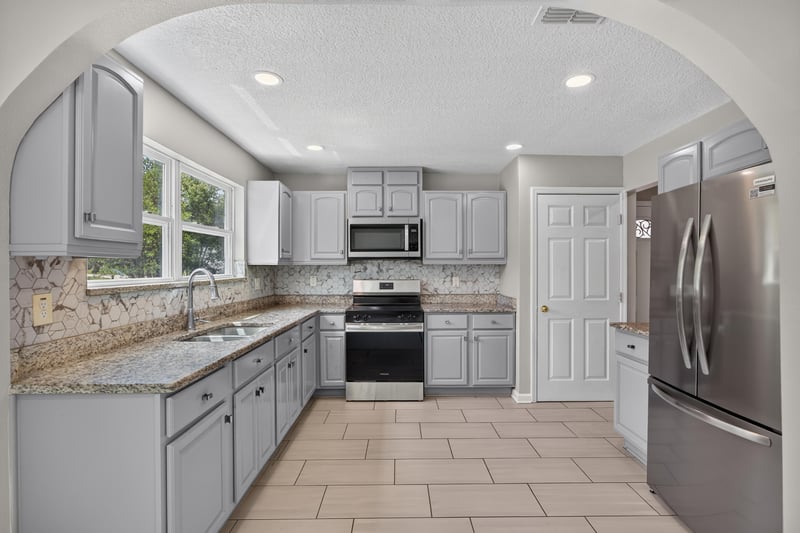Kitchen with gray cabinets and stainless refrigerator at 7015 Miss Muffet Ln N, Jacksonville, FL 32210