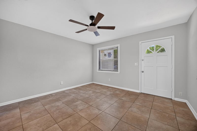 Empty living room with ceiling fan, tile floor and front door at 7453 Jade Dr N, Jacksonville, FL 32210