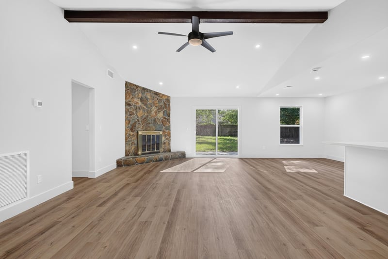 Living room with stone fireplace wall and wood flooring at 8453 Boysenberry Ln W, Jacksonville, FL